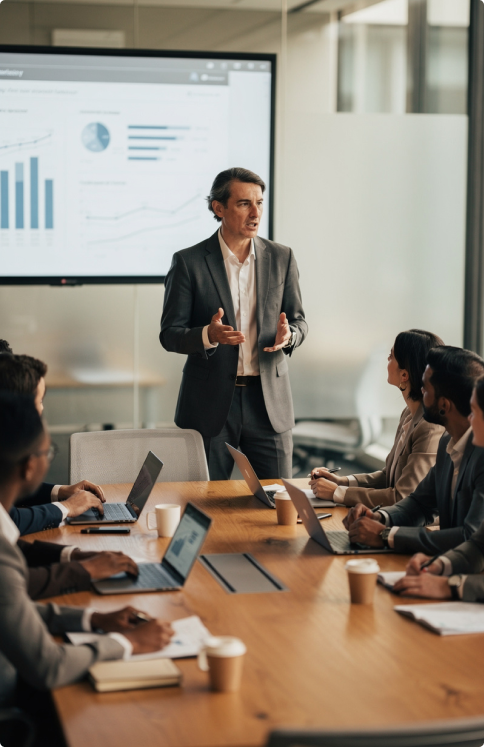 Image of a man in his 50s presenting trade data to colleagues. They are in a modern office setting
